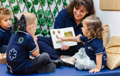 teacher holding a book for children to learn